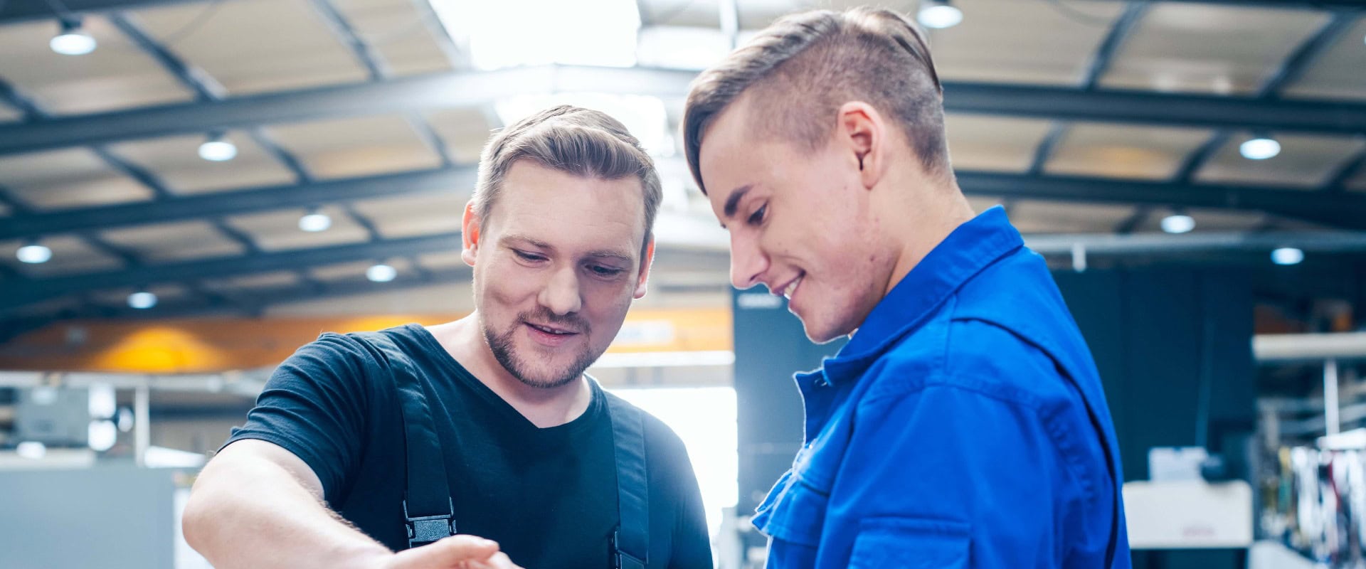 Meister bespricht ein Werkstück mit seinem Lehrling oder Auszubildenden